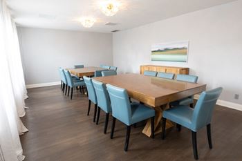 a dining room with a long wooden table with blue chairs and a painting on the wall  at Pheasant Run, Lafayette, Indiana